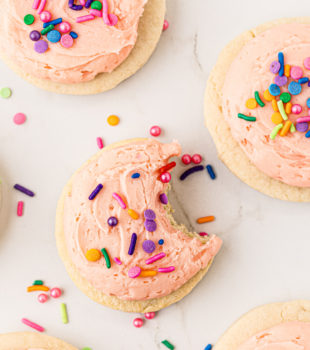 overhead view of a Lofthouse cookie with a bite missing surrounded by more cookies and sprinkles