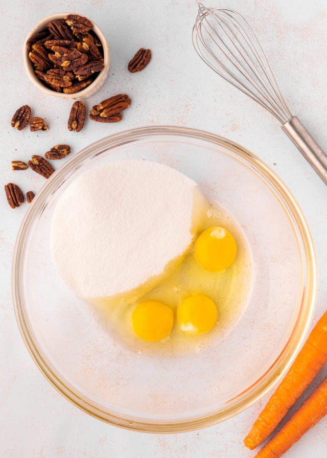 overhead view of sugar and eggs in a glass mixing bowl