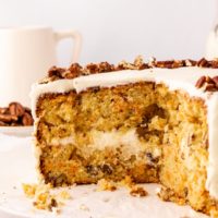 a partially cut carrot cake topped with chopped pecans, showcasing the moist cake layers and creamy frosting