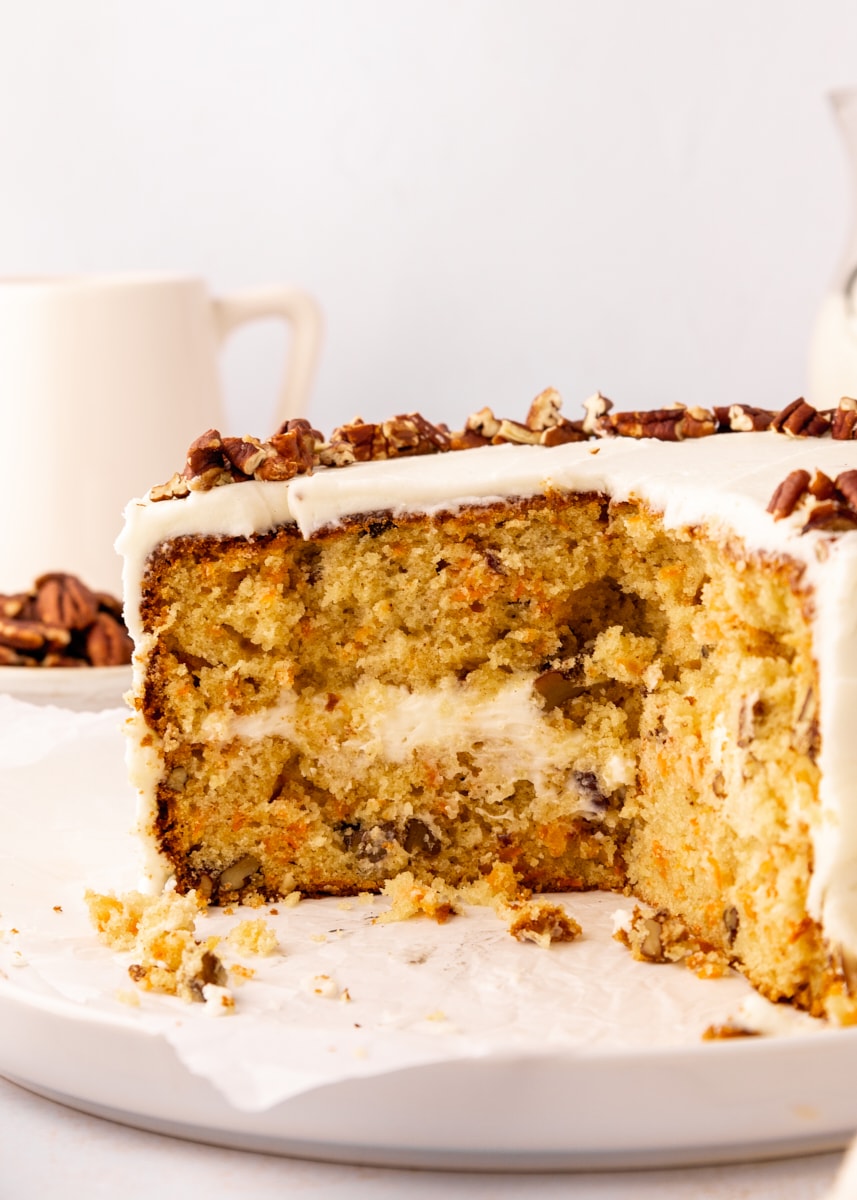 a partially cut carrot cake topped with chopped pecans, showcasing the moist cake layers and creamy frosting