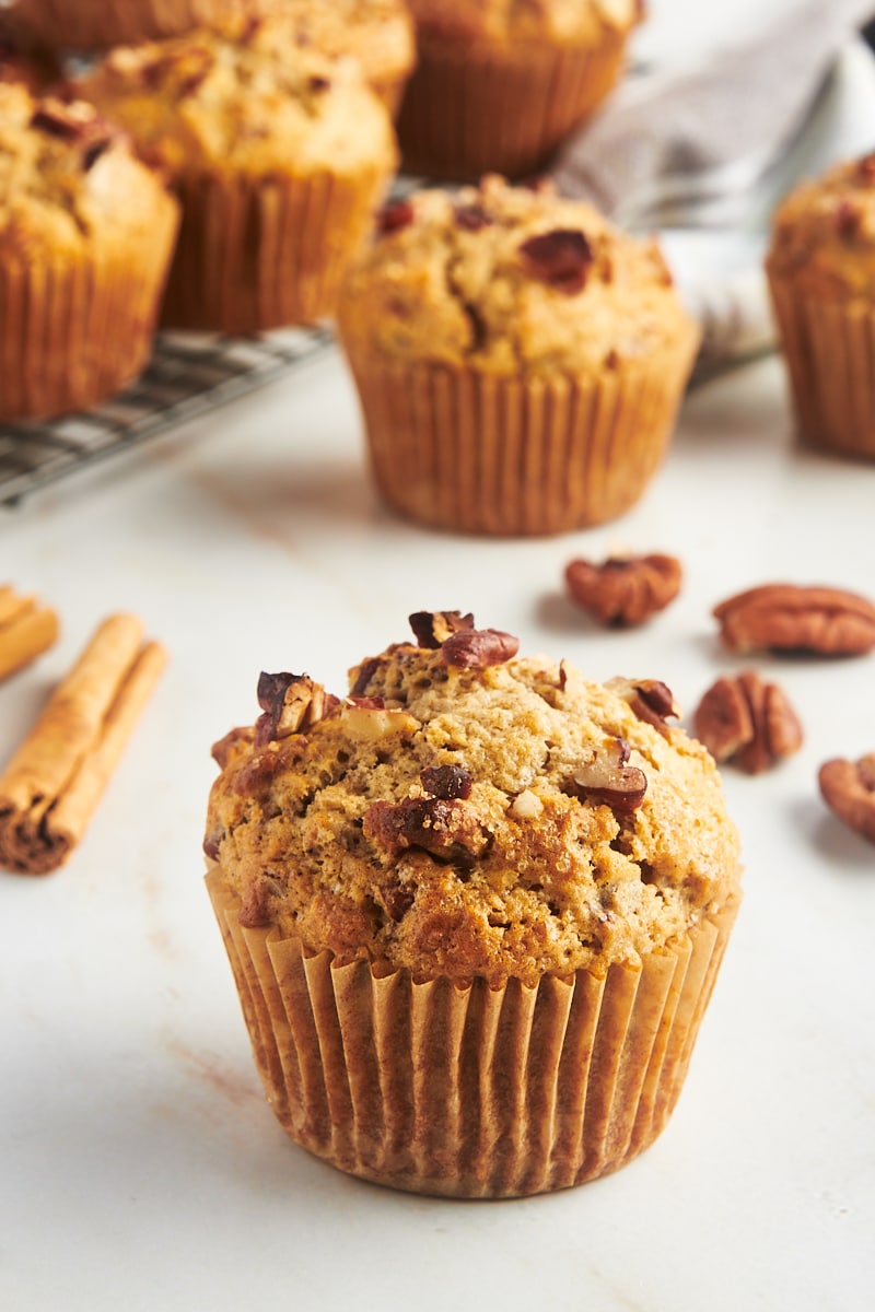 Moist cinnamon pecan muffin on countertop with additional muffins in background