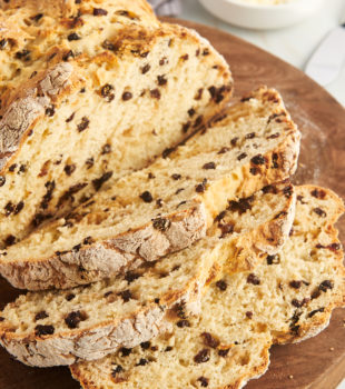 partially sliced Irish soda bread on a round wooden board