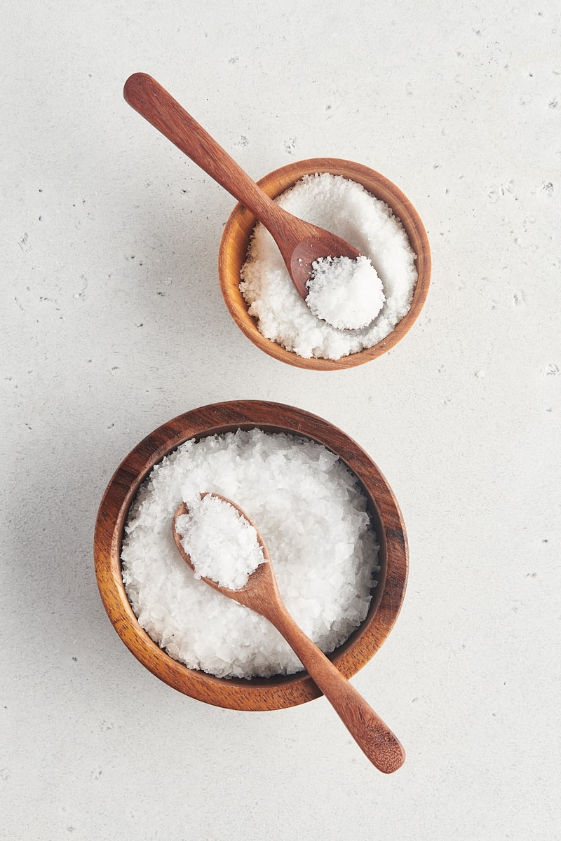 overhead view of fine sea salt and large flake sea salt in wooden bowls