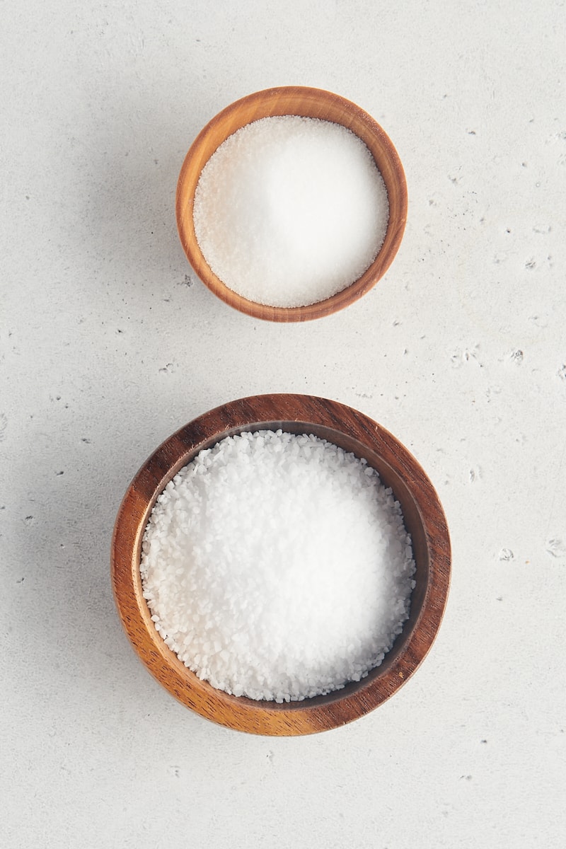 overhead view of table salt and kosher salt in wooden bowls