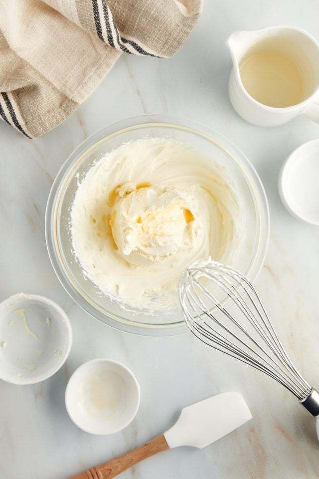 overhead view of mascarpone and vanilla extract added to sweetened whipped cream