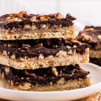 a stack of three butter pecan turtle bars on a white plate