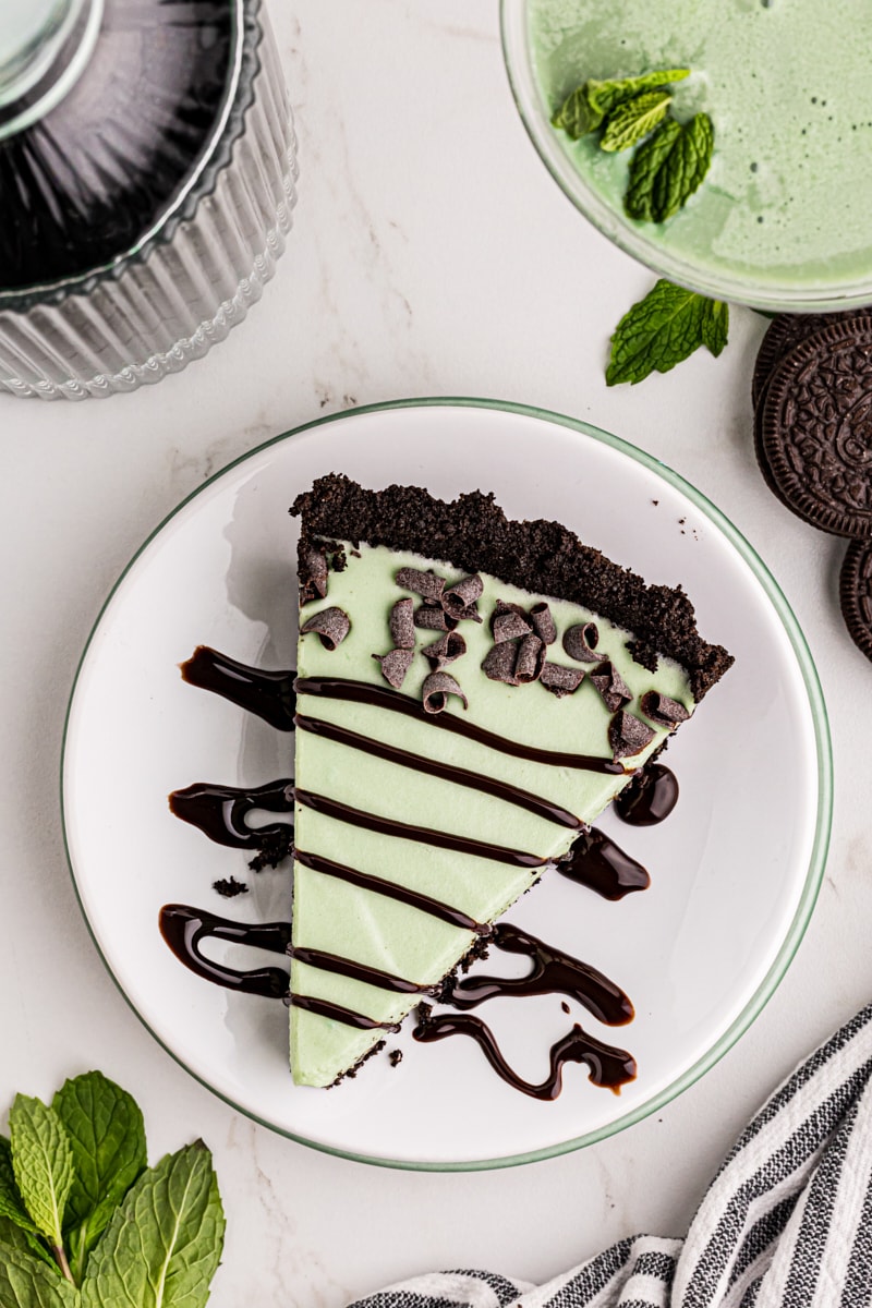 overhead view of a slice of grasshopper pie topped with chocolate curls and chocolate syrup
