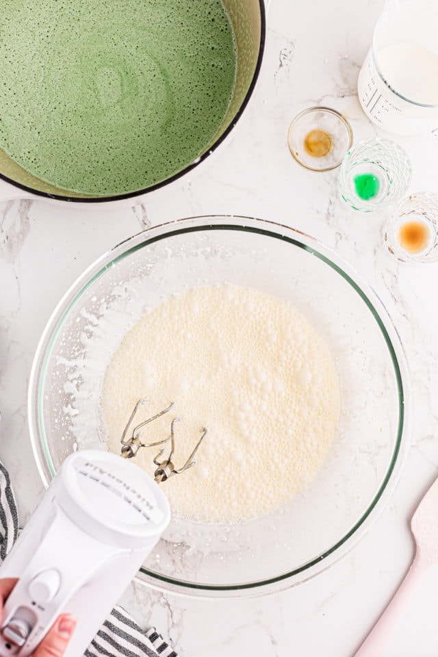 overhead view of cream being whipped in a glass mixing bowl