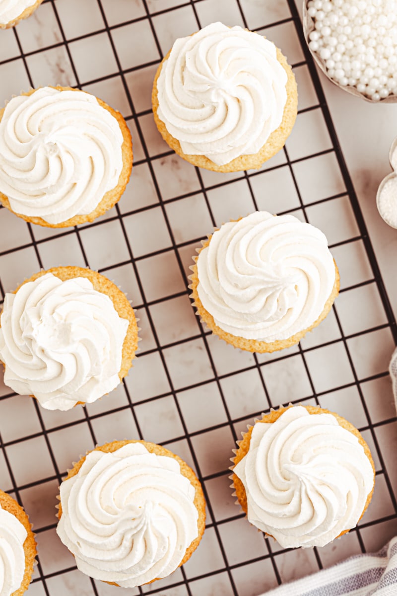 overhead view of frosted vanilla cupcakes on a wire rack