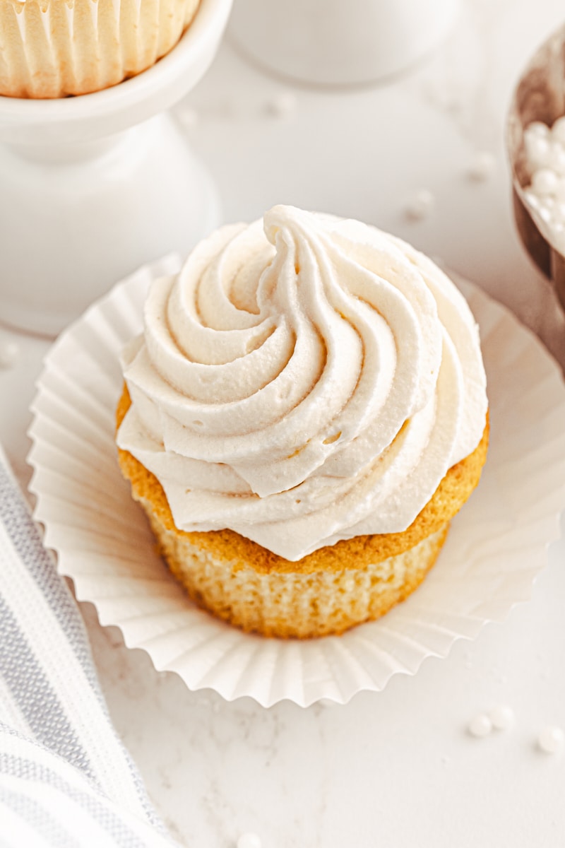 a partially unwrapped vanilla cupcake