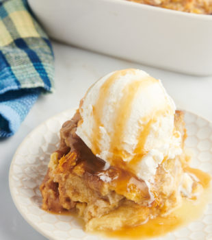 Piece of banana bread pudding on plate with ice cream and caramel on top