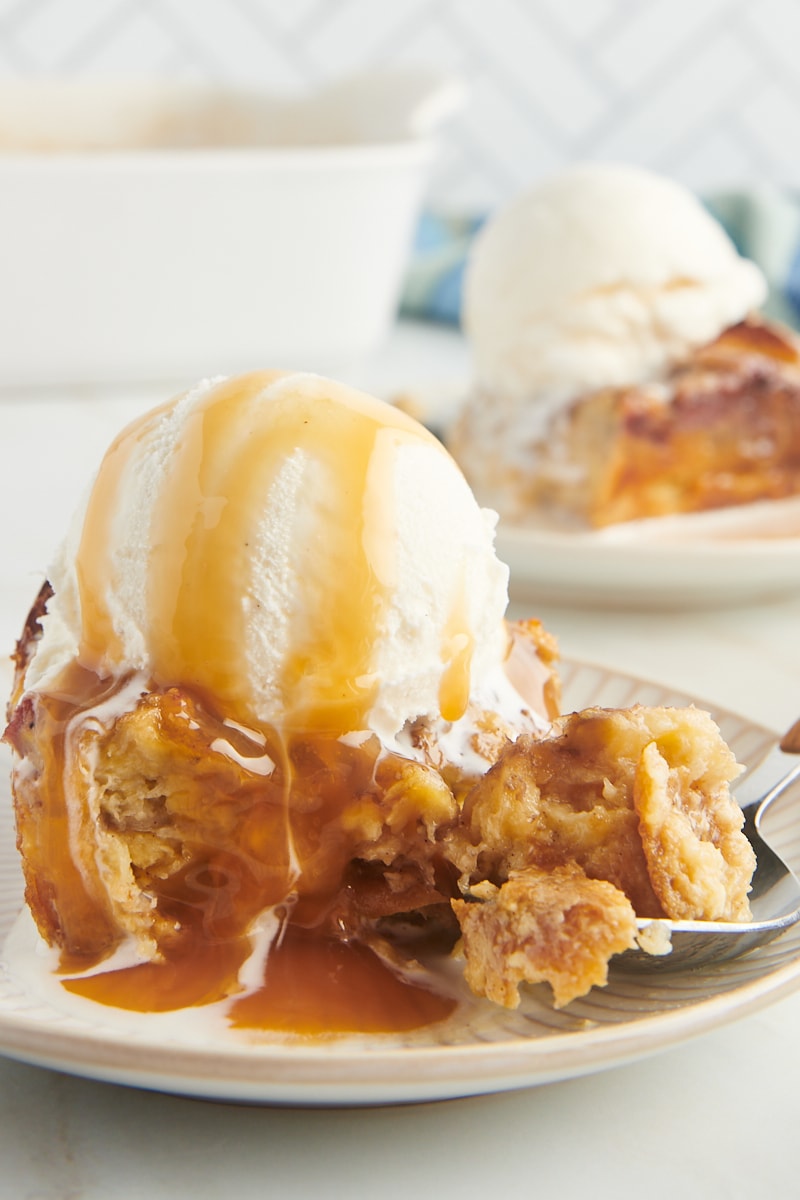 Plate with serving of banana bread pudding topped with scoop of ice cream and caramel