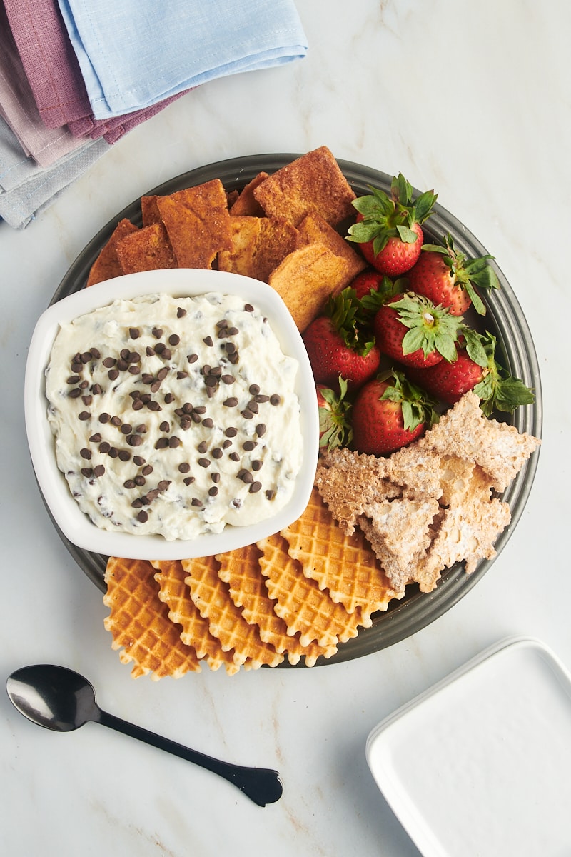 overhead view of cannoli dip in a white bowl along with various dippers on a pewter tray