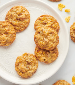 Plate of cornflake cookies with additional cookies on tabletop