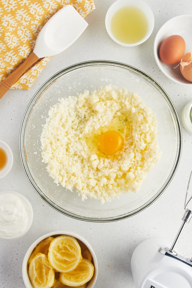 Overhead view of first egg cracked into creamed butter and sugar