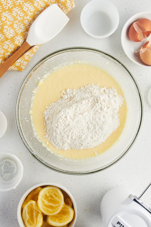 Overhead view of flour added to bowl of wet ingredients for lemon loaf