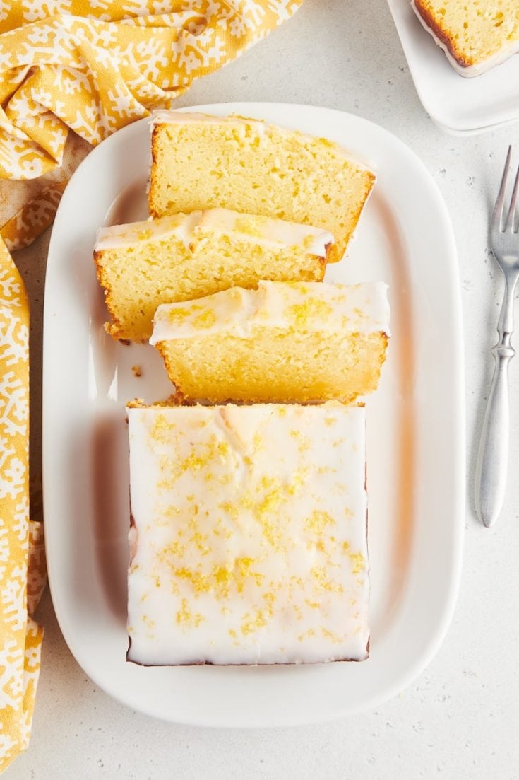 Overhead view of half sliced lemon loaf cake on platter