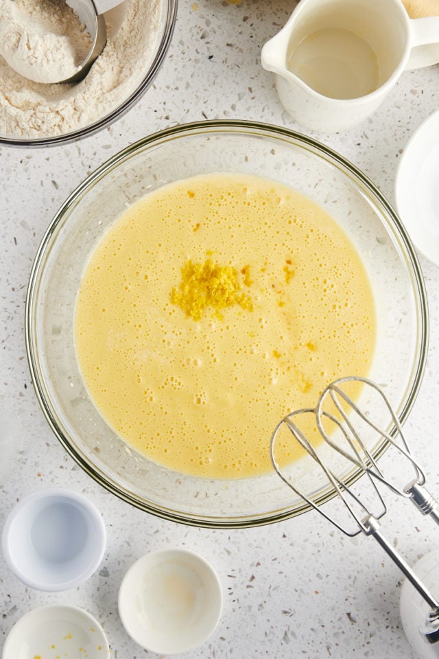 overhead view of milk, lemon zest, lemon juice, and vanilla extract added to olive oil cake batter