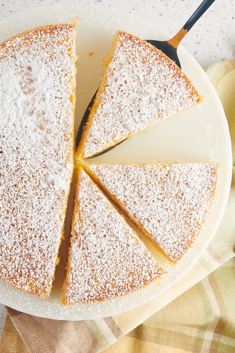 overhead view of partially sliced olive oil cake on a white cake stand