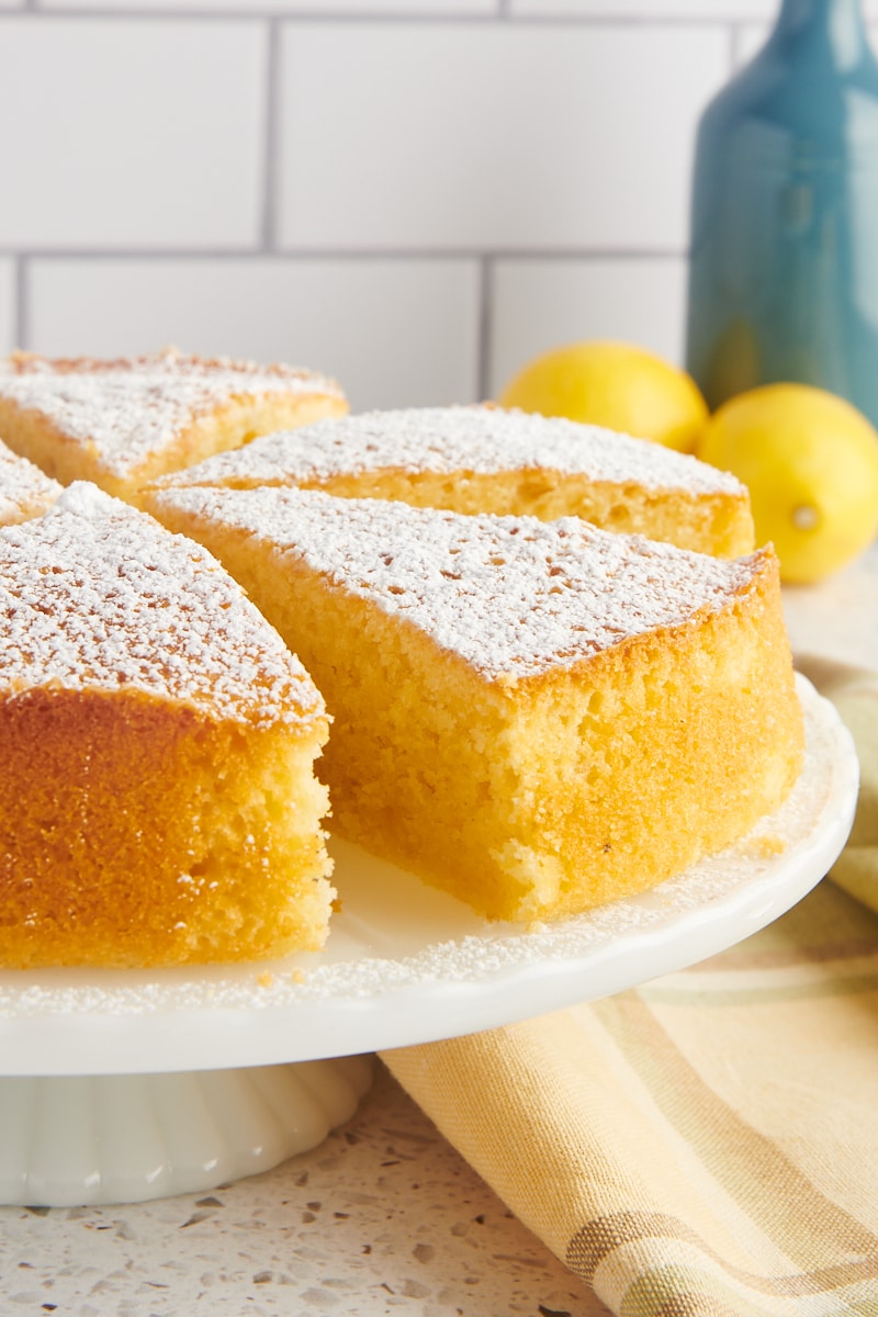 partially sliced olive oil cake on a white cake stand