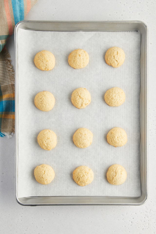 overhead view of freshly baked sour cream cookies on a parchment-lined baking sheet