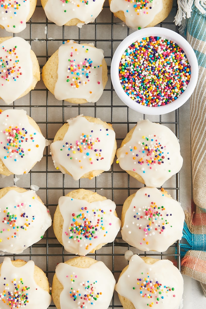 overhead view of sour cream cookies and a small bowl of sprinkles on a wire rack