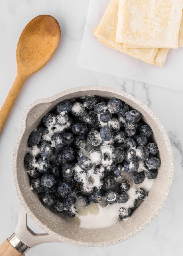 overhead view of blueberries, lemon juice, and sugar in a saucepan