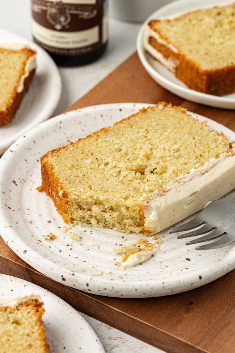 a slice of brown butter pound cake with a bite missing on a white plate