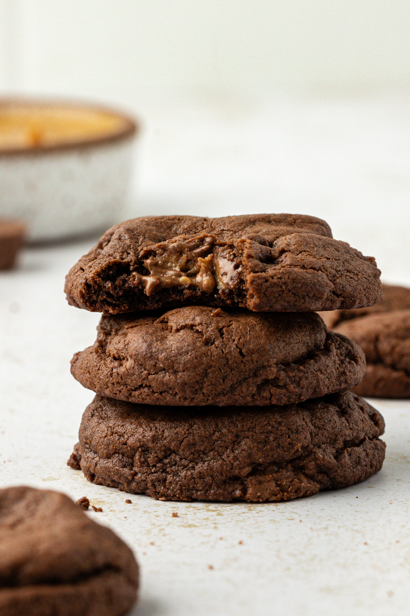 a stack of three chocolate peanut butter cookies with a bite missing from the top cookie