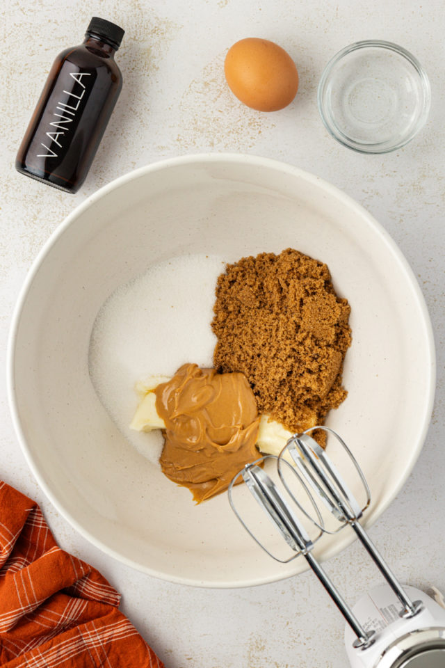 overhead view of butter, peanut butter, sugar, and brown sugar in a white mixing bowl