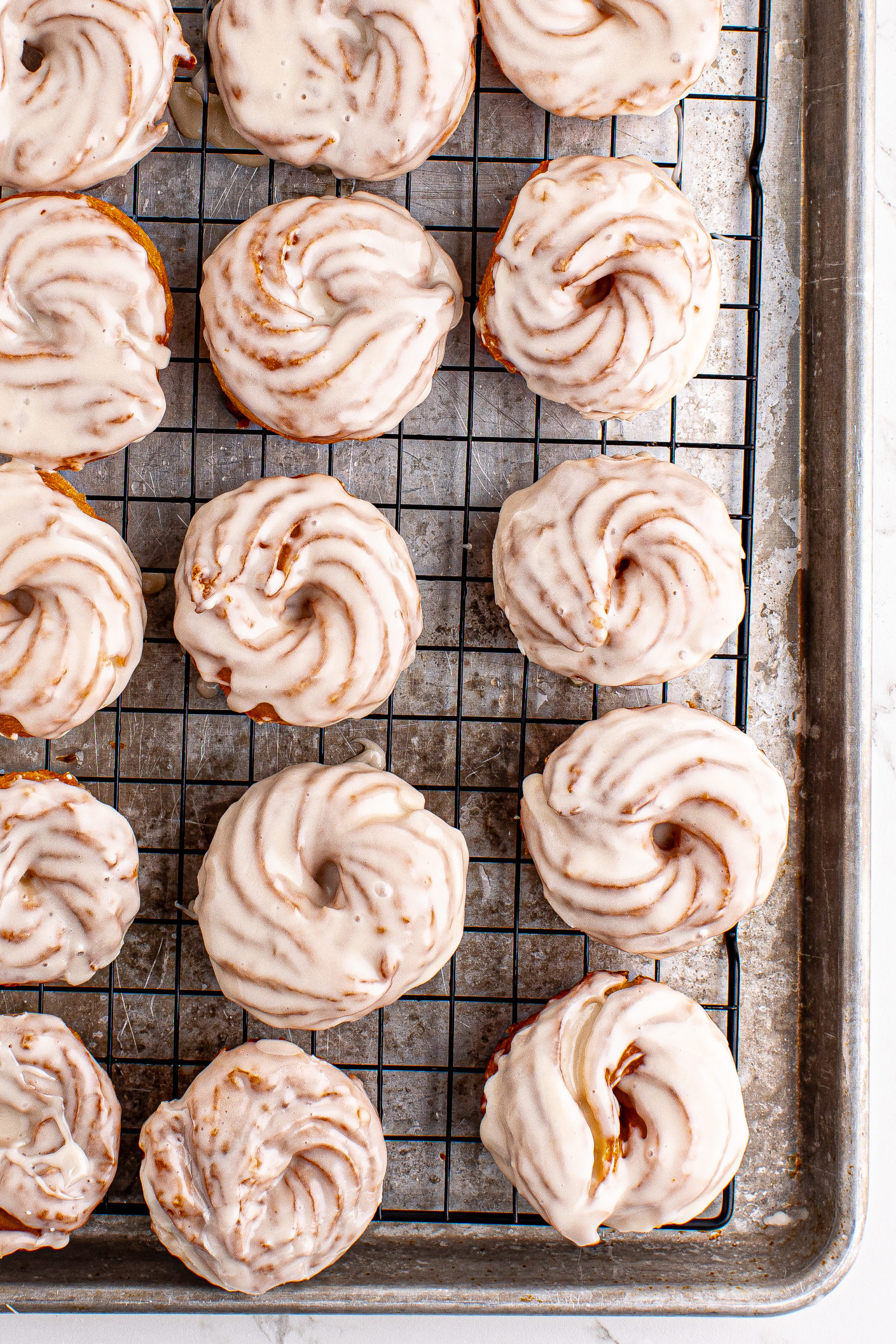 Overhead view of French crullers on wire rack set on sheet pan