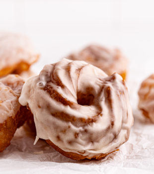 Glazed French crullers on crinkled parchment paper