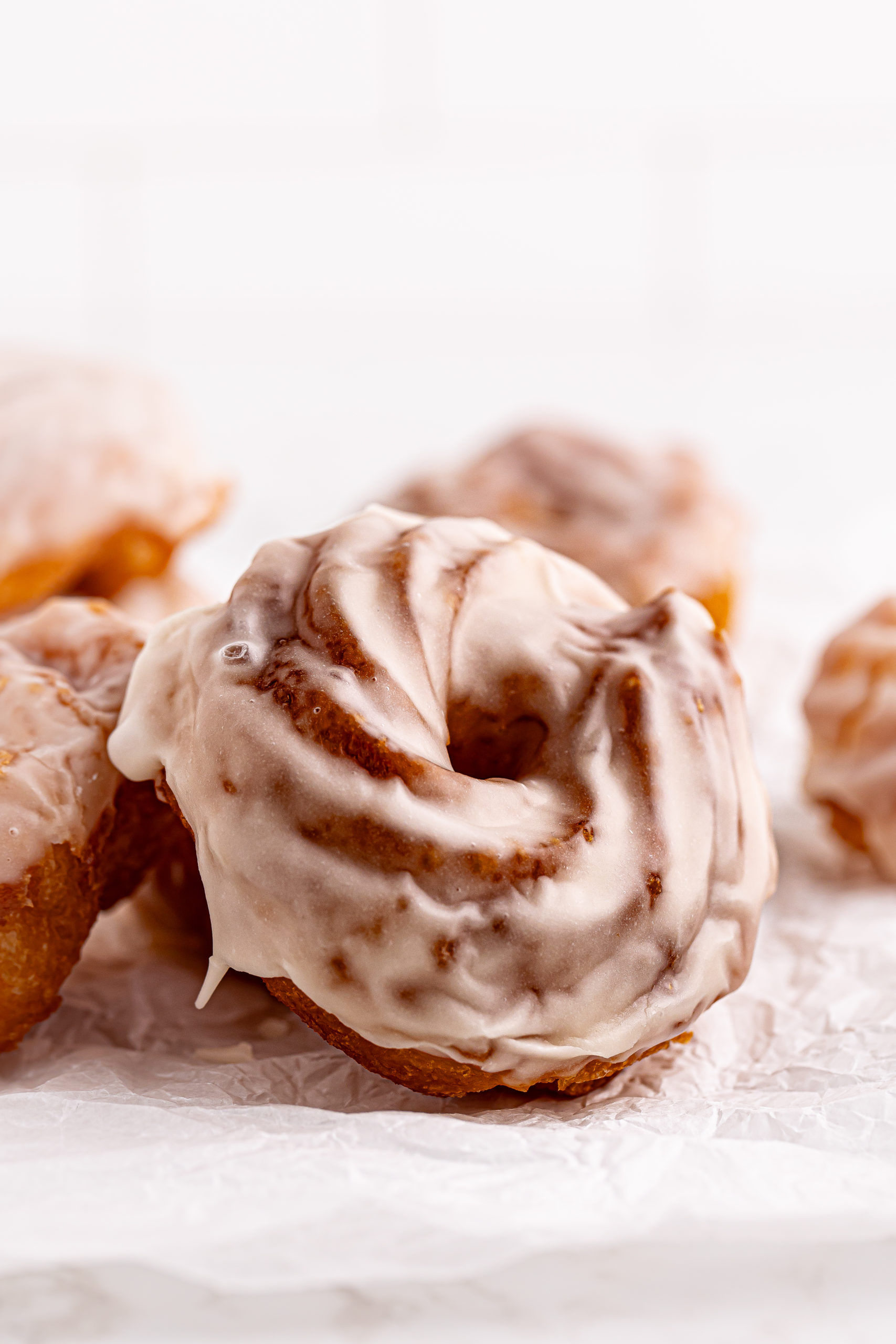 Glazed French crullers on crinkled parchment paper