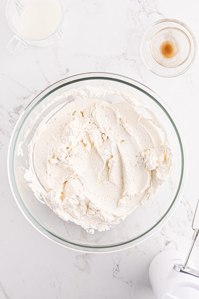 overhead view of freshly whipped cream in a glass mixing bowl