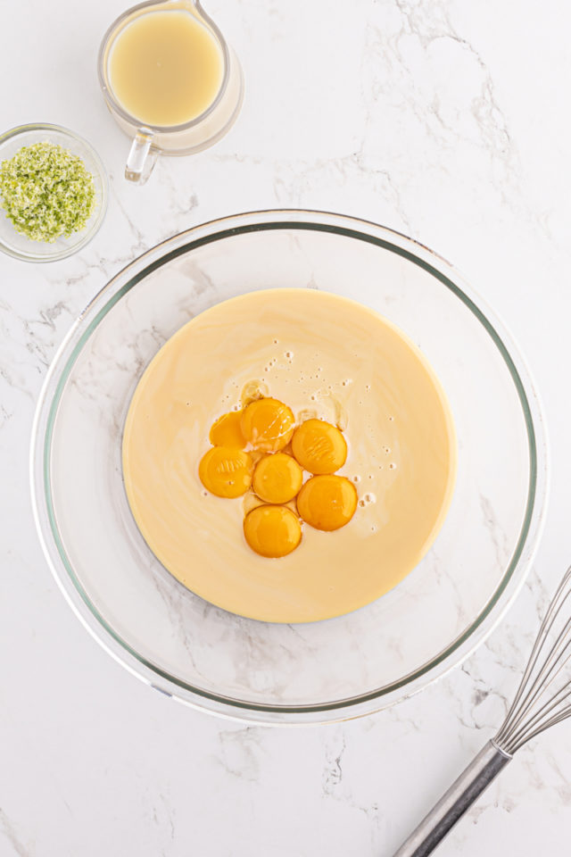 overhead view of sweetened condensed milk and egg yolks in a glass mixing bowl
