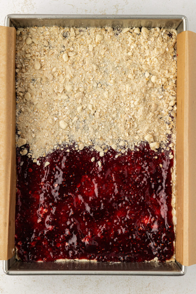 overhead view of raspberry jam spread onto oat crust and partially topped with oat topping