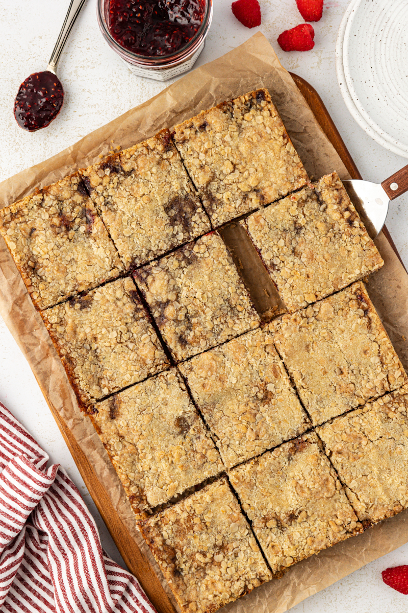overhead view of raspberry oatmeal bars cut into bars on a wooden cutting board