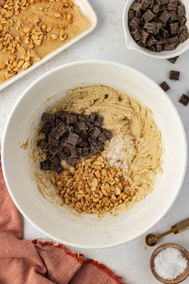 overhead view of chocolate chunks, peanuts, and sea salt added to peanut chocolate chunk cookie dough