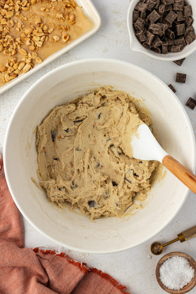 overhead view of mixed peanut chocolate chunk cookie dough in a white mixing bowl