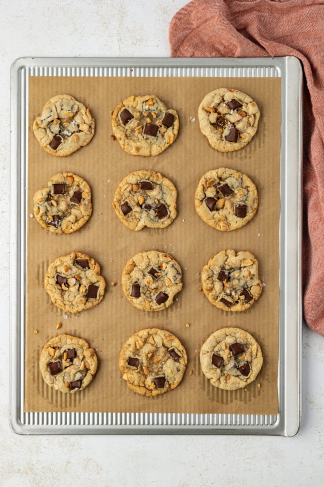 overhead view of freshly baked peanut chocolate chunk cookies on a parchment-lined baking sheet