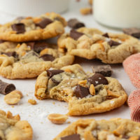 a peanut chocolate chunk cookie with a bite missing, surrounded by more cookies