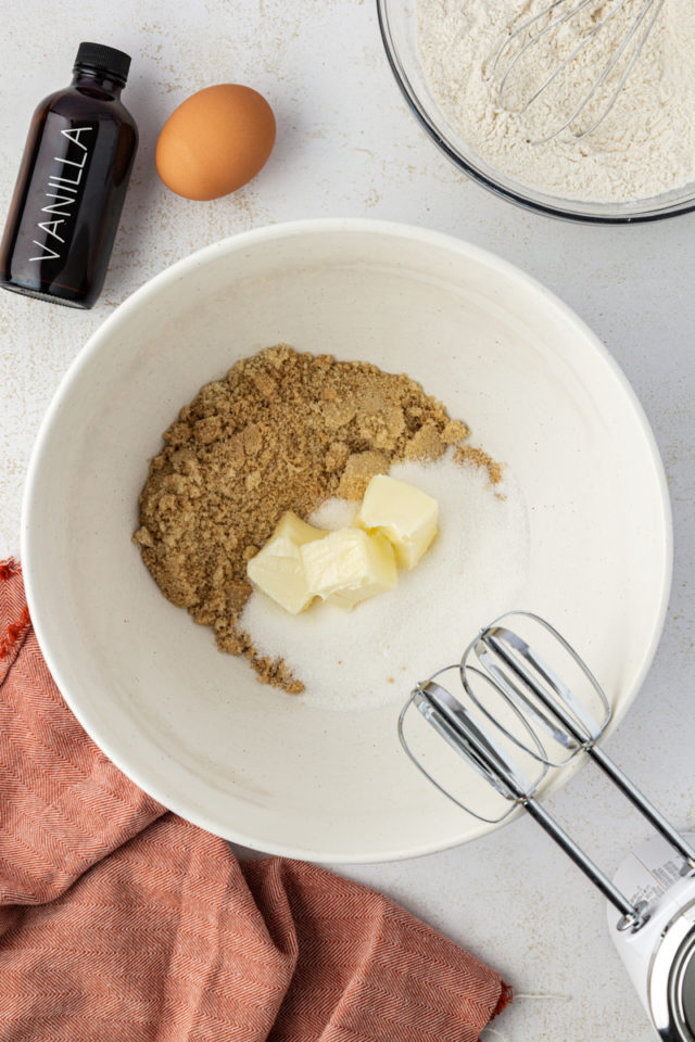 overhead view of butter, brown sugar, and sugar in a white mixing bowl