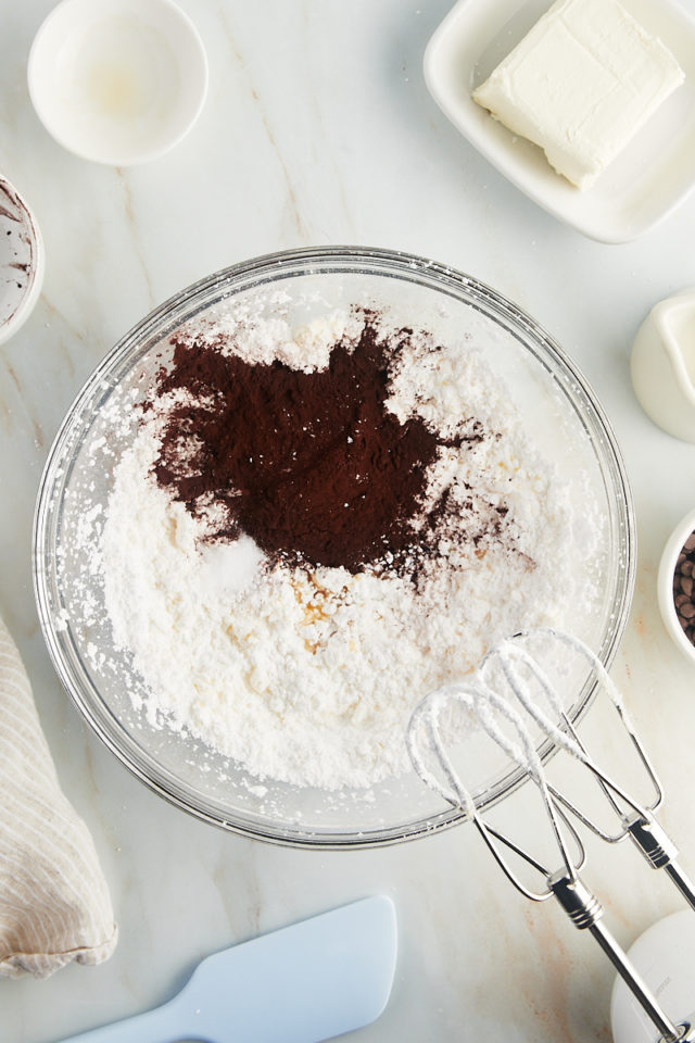 overhead view of cocoa powder, vanilla extract, and salt added to creamed butter and confectioners' sugar