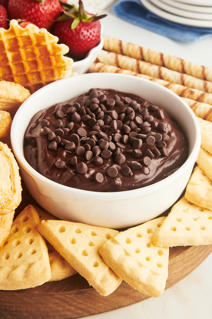 a bowl of brownie batter dip surrounded by various dippers on a wooden board