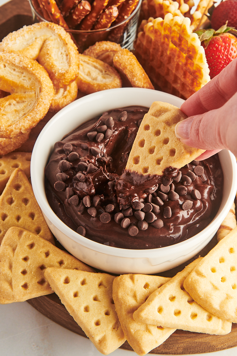 a shortbread cookie being dipped into a bowl of brownie batter dip
