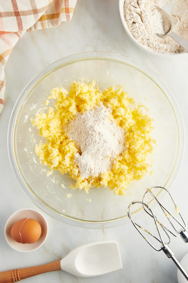 Overhead view of dry ingredients added to bowl of creamed butter and sugar