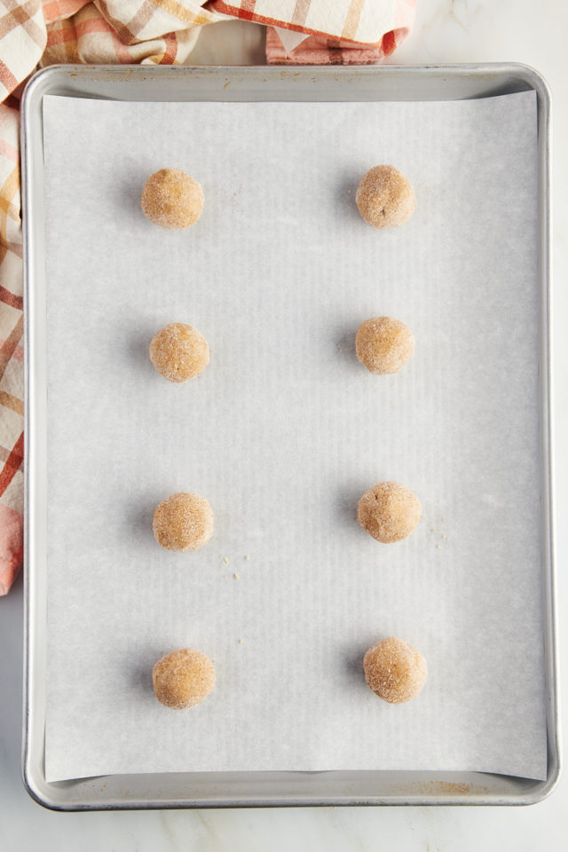 Overhead view of cookie dough balls on parchment-lined baking sheet