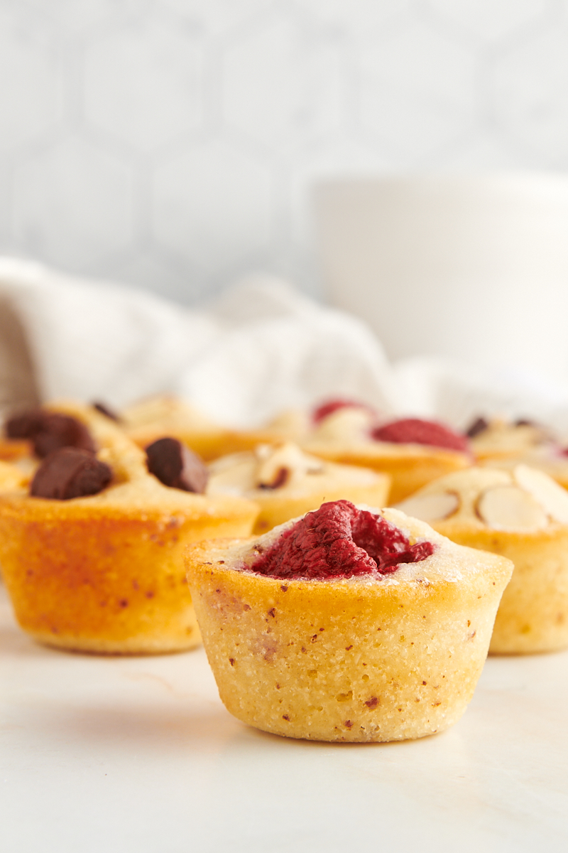 a raspberry-topped financier on a marble countertop with more financiers in the background