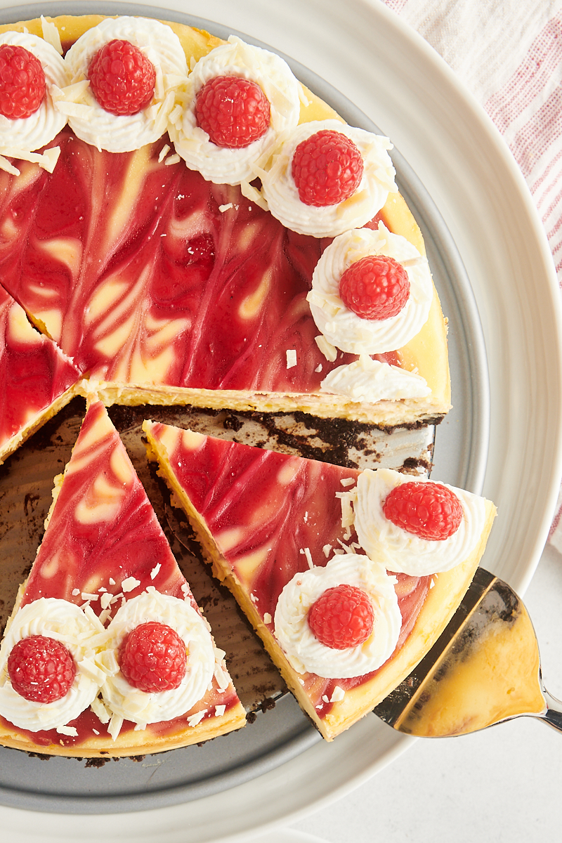 Overhead view of cut white chocolate raspberry cheesecake on platter