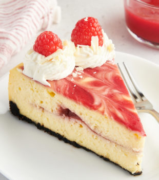 Slice of white chocolate raspberry cheesecake on white plate
